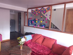 A living room with a red sofa, a glass coffee table, and a decorative wall hanging. - The Awakening of the Inca (Cusco)