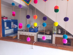 A kitchen with a stove, sink, and blue shelving unit. - The Awakening of the Inca (Cusco)