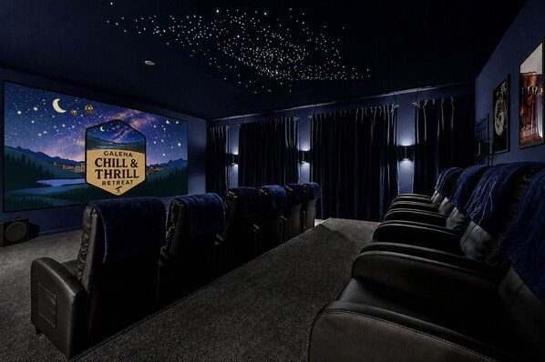 Une salle plongée dans l’obscurité, avec un plafond constellé d’étoiles, un grand écran diffusant une scène nocturne, et des rangées de fauteuils inclinables en cuir.