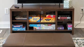 A living room with a flat-screen TV on a wooden stand, a remote control, and a tissue box on the stand.