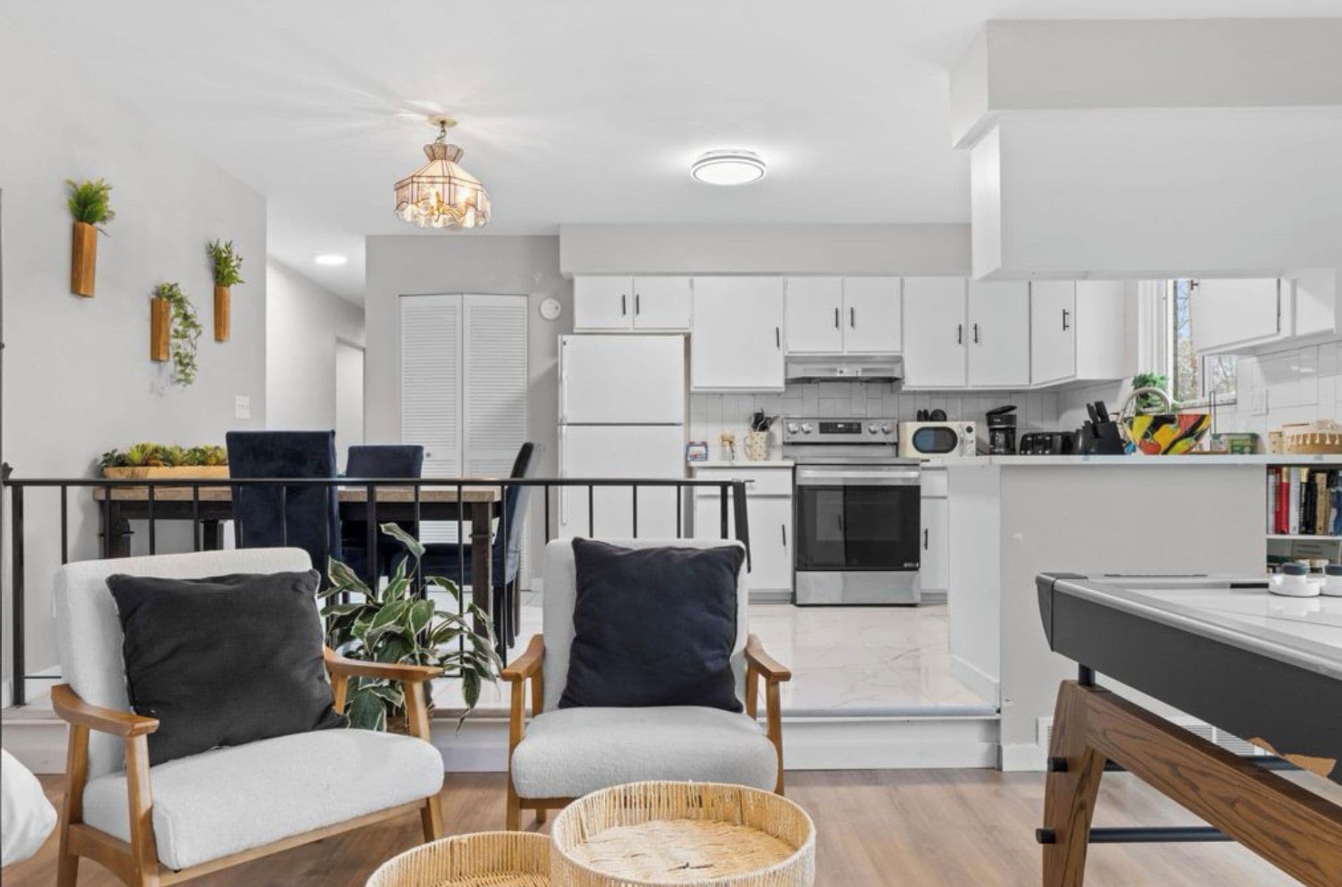 A modern kitchen with white cabinets, a dining area with a table and chairs, and a living space with a sofa and a coffee table.