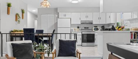 A modern kitchen with white cabinets, a dining area with a table and chairs, and a living space with a sofa and a coffee table.