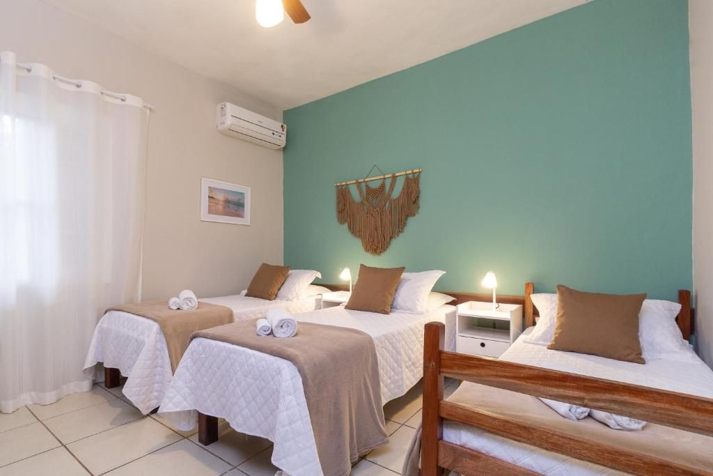 Een hotelkamer met twee bedden, een houten stoel, een nachtkastje met een lamp en een wandairconditioner.