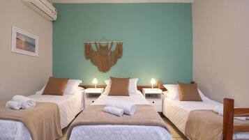 Een hotelkamer met twee bedden, een muur in teal en een macramé wandversiering.