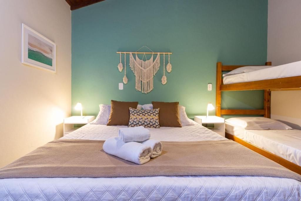 Una habitación de hotel con cama, literas, un cuadro en la pared y dos lámparas de noche.