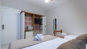 Un dormitorio con dos camas, un armario, un escritorio y un ventilador de techo.