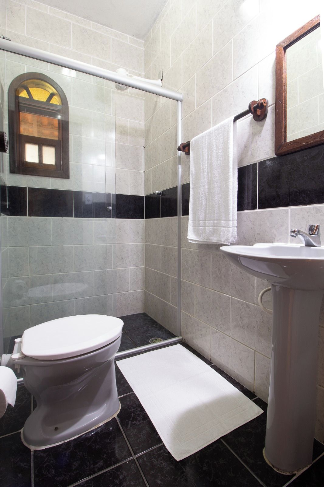 Un baño con inodoro, lavamanos y cabina de ducha.