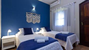 Een hotelkamer met twee bedden, een wanddecoratie, een airconditioning en een deur.