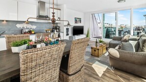 A modern living space with a dining area, kitchen, and a large window overlooking a marina. - Houseboat in Olpenitz With Swimming Pool (Kappeln)