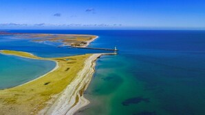 An aerial view of a coastal area with a lighthouse, clear blue waters, and a sandy beach. - Houseboat in Olpenitz With Swimming Pool (Kappeln)