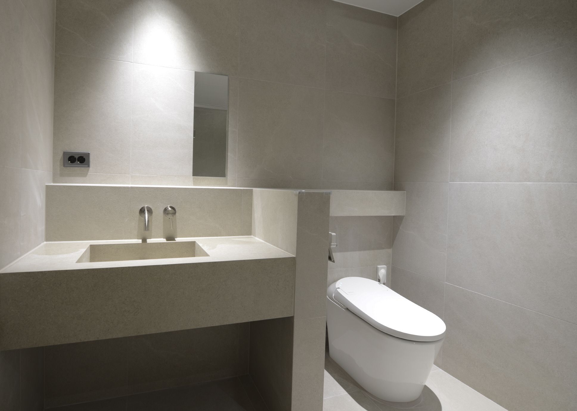 Ein modernes Badezimmer mit Waschbecken, Spiegel und Toilette.