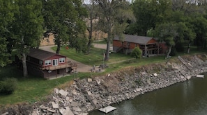 A lakeside property with two main buildings, a dock, and a rocky shoreline.