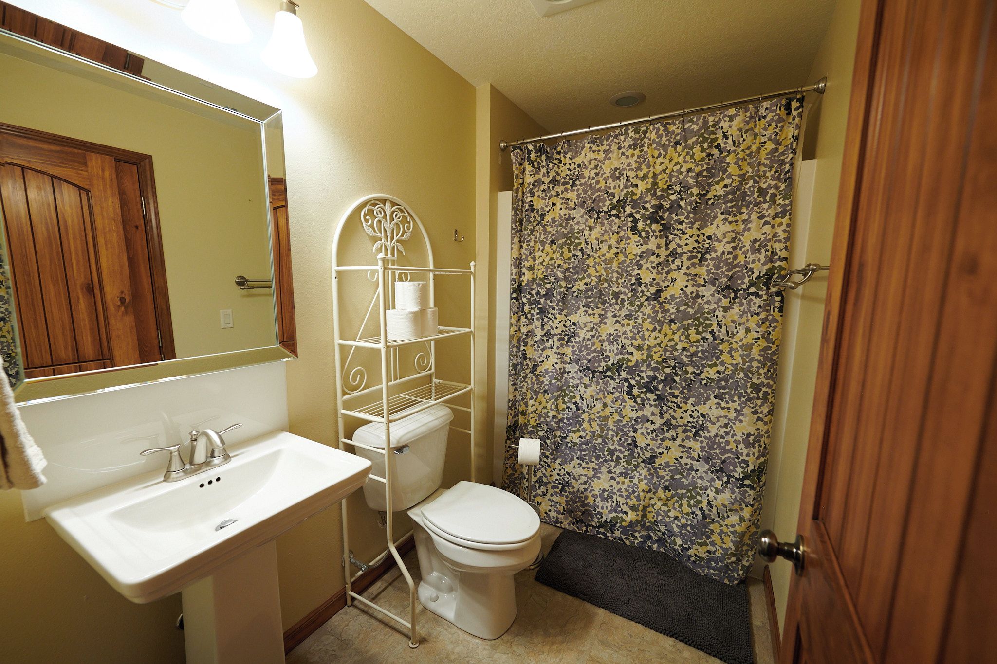 A bathroom with a white sink, toilet, and shower curtain.
