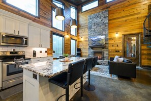 Una cocina moderna con una isla grande, electrodomésticos integrados y una chimenea de piedra.