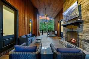 Un interior de madera con chimenea, muebles de mimbre y vistas al exterior.