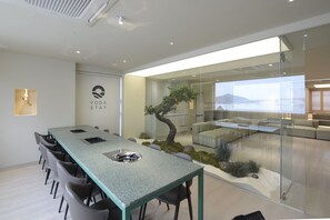 Ein moderner Konferenzraum mit Glastrennwand, einer Bonsai-Pflanze und Blick auf eine Stadtlandschaft.