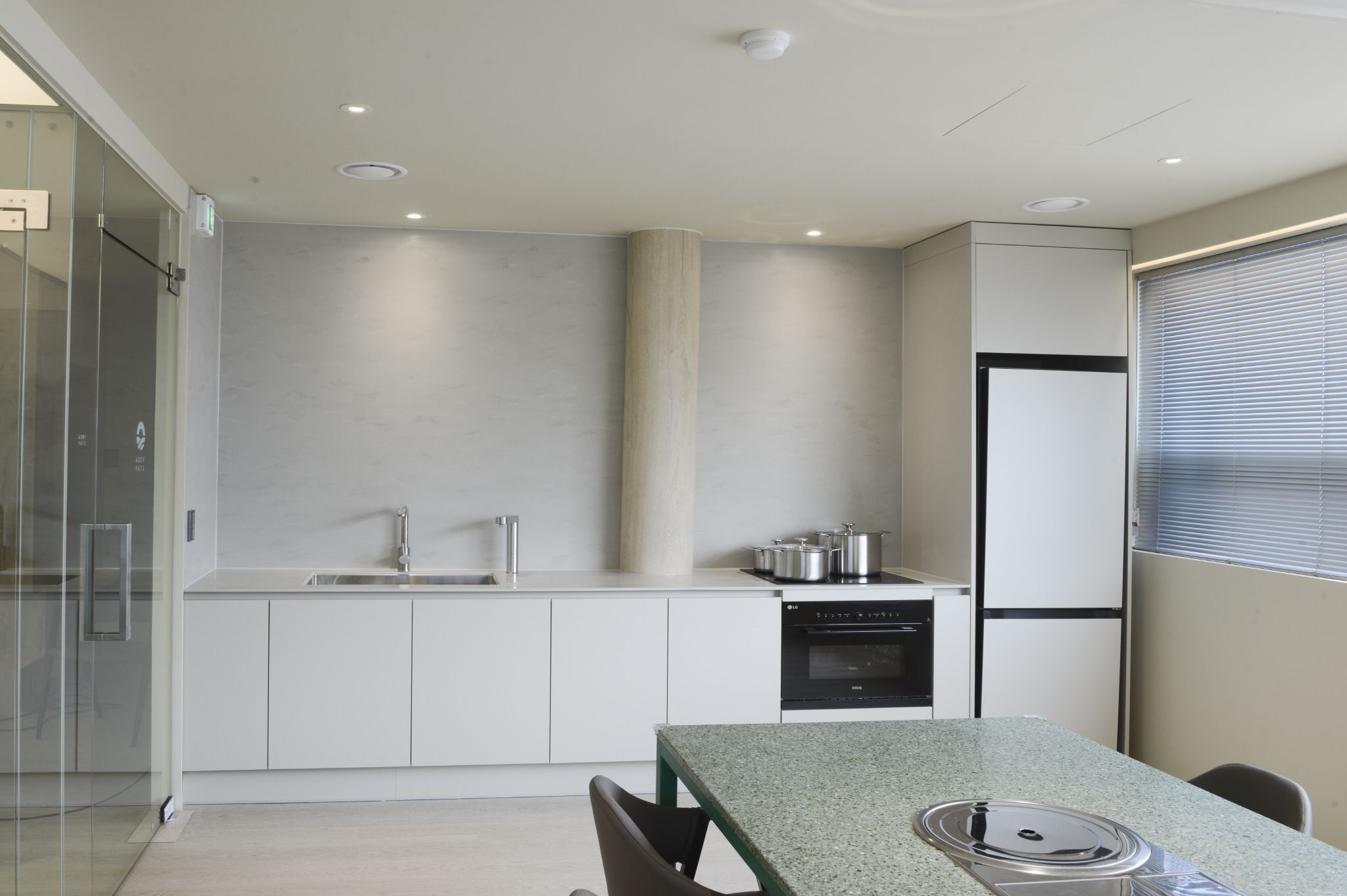 Eine moderne Küche mit Backofen, Kühlschrank und Essbereich mit Tisch und Stühlen.