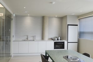 Eine moderne Küche mit Backofen, Kühlschrank und Essbereich mit Tisch und Stühlen.