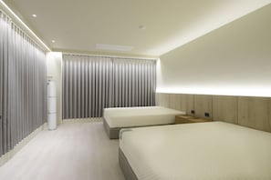 Ein Hotelzimmer mit zwei Betten, einem großen Fenster mit Vorhängen, einem Holz-Kopfteil und einer weißen Wand.