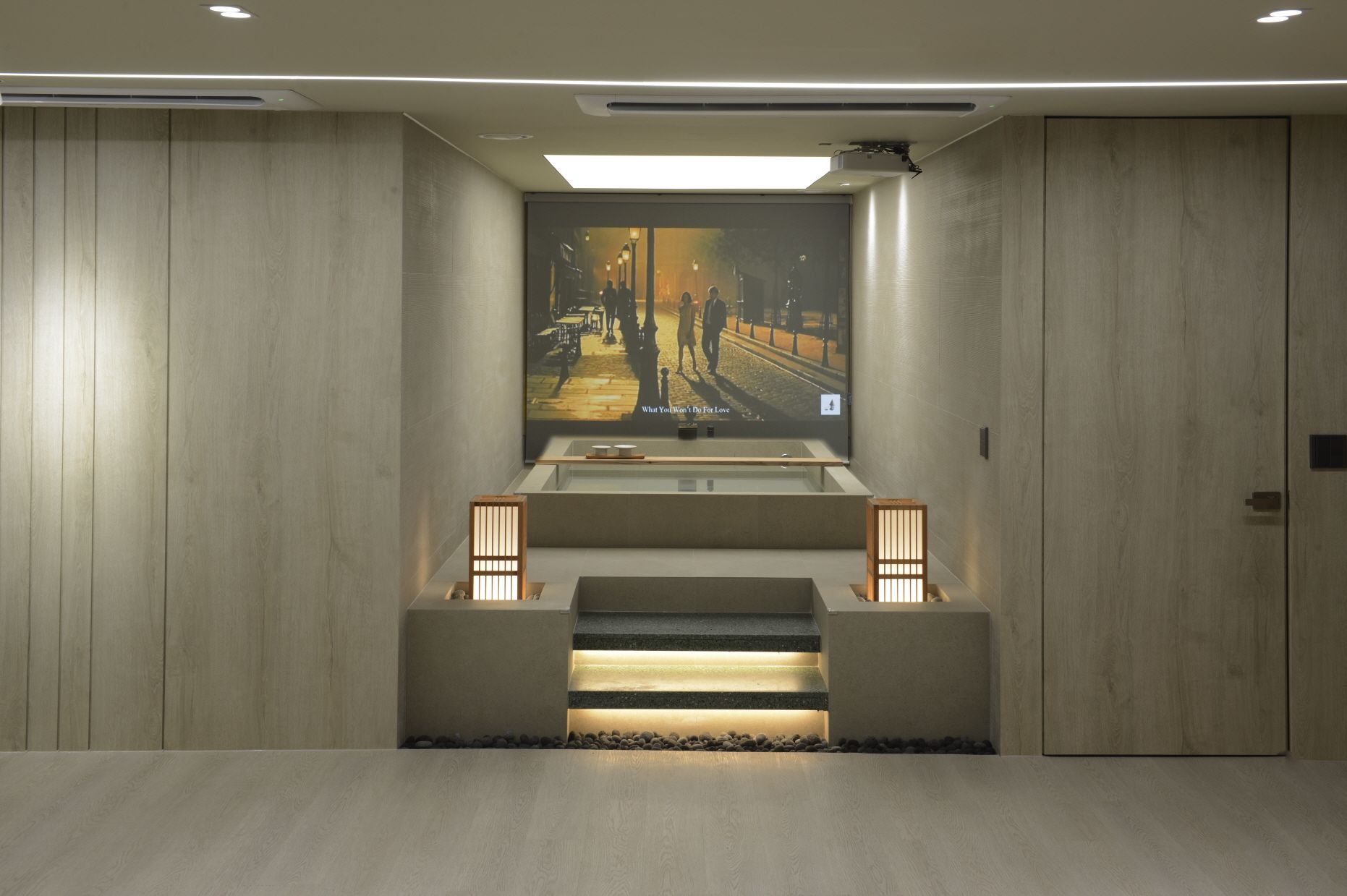Ein modernes Interieur mit Holzboden, einer zentralen Treppe und einem gerahmten Kunstwerk darüber.