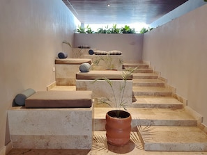 A staircase with beige steps and cushions, leading to a landing with a potted plant. - 5th Ave. Studio Ocean View Rooftop (Playa del Carmen)