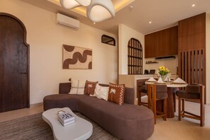 A modern living room with a sectional sofa, a dining area with wooden chairs, and a kitchen with wooden cabinets. - NEW 3BR Boutique Villa w/ Private Pool - Bingin (South Kuta)