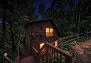 Eine Holzhütte mit einer Veranda und einer Treppe, umgeben von Bäumen.