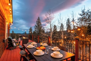 An outdoor dining area with a table set for four, surrounded by chairs, and a grill in the background. - Modern Private 3 Acres w/ Hot Tub and Game Room (Bailey)