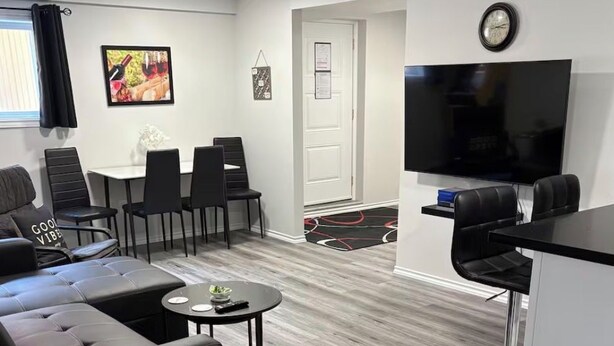 Un soggiorno moderno con un divano, poltrone, un tavolino, una TV e un angolo bar.