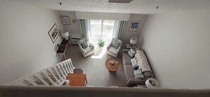 A spacious living area with a sofa, a coffee table, and a staircase leading to another level. - Steps from Wells Beach, Bellevue by the Sea is perfect for your Maine vacation (Wells)
