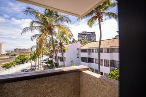 Varanda com vista para palmeiras e edifícios.