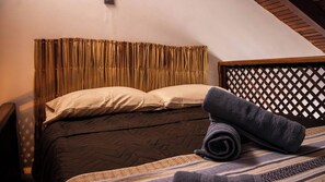 A bed with a headboard, pillows, and a rolled towel.