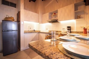 A modern kitchen with a built-in refrigerator, granite countertops, and a dining area set for four.
