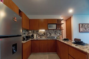 Eine Küche mit Holzschränken, einem Edelstahlkühlschrank, einer Mikrowelle und einem Spülbecken.