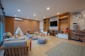 Ein modernes Wohnzimmer mit Fernseher, Sitzgelegenheiten, einem Bücherregal und einer zeltartigen Konstruktion.