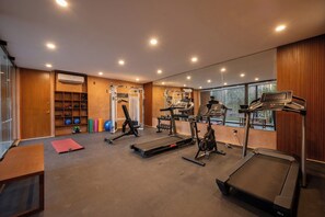 Ein Fitnessstudio mit Laufbändern, Trainingsgeräten und einer Spiegelwand.