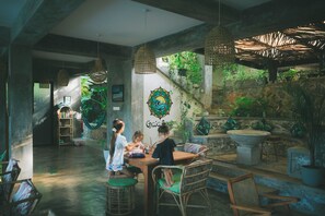 Un espace intérieur accueillant, doté d’un escalier, de luminaires suspendus et de plantes vertes.