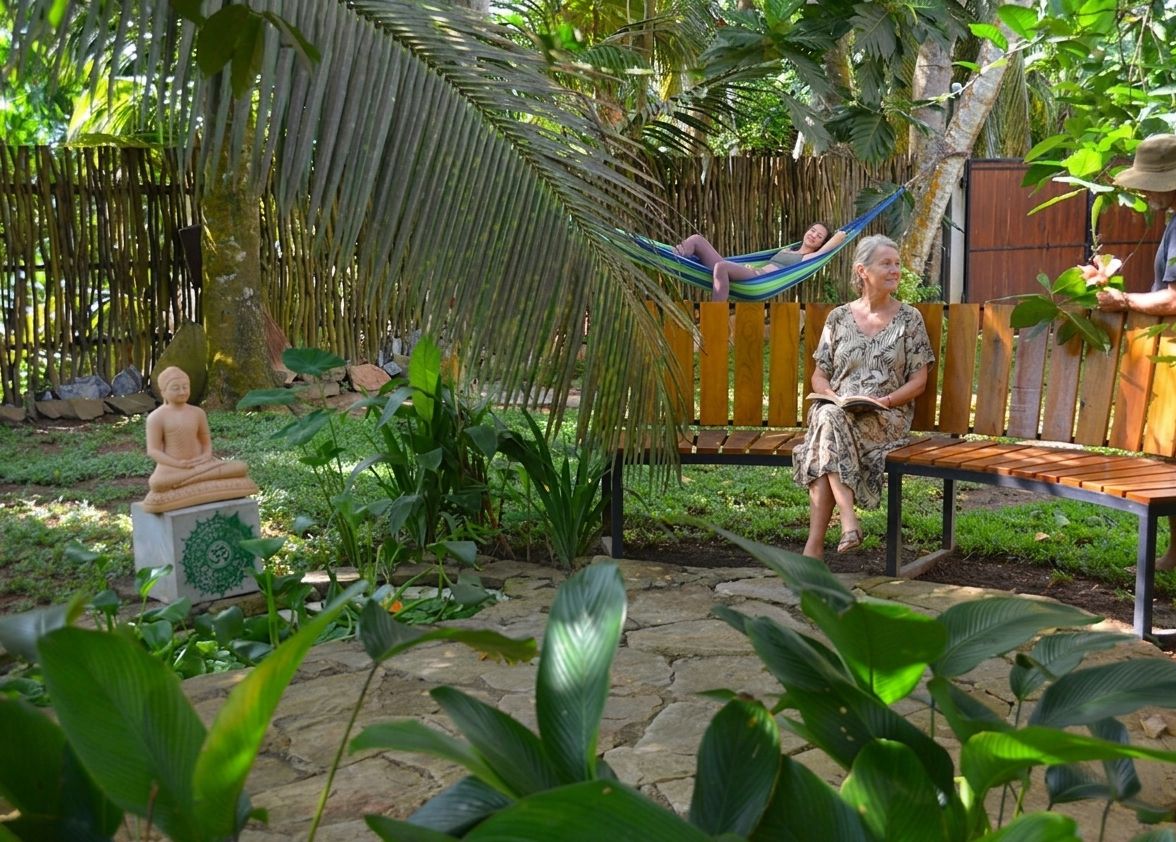 A garden with a wooden bench, a hammock, and a statue.