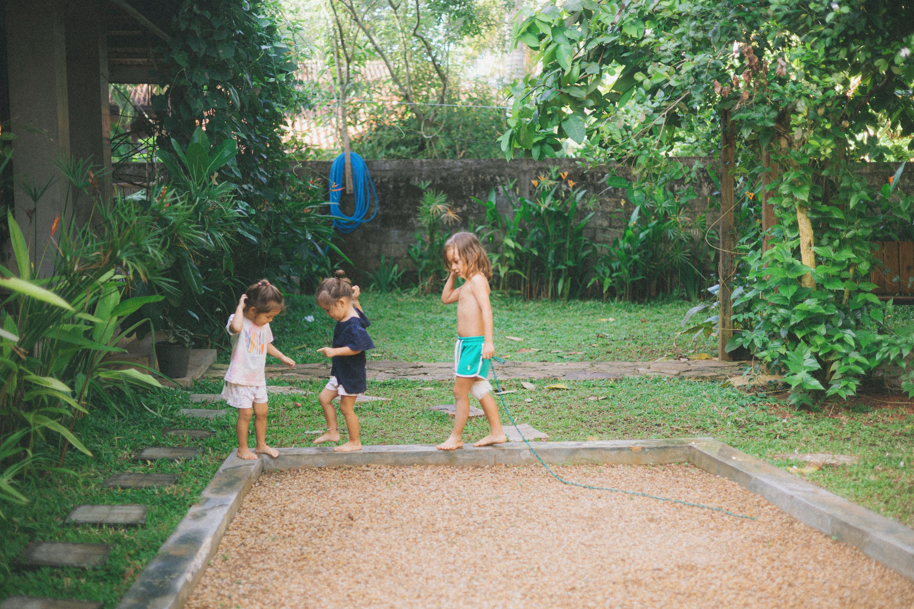 A garden with a wooden play area and a blue hose.