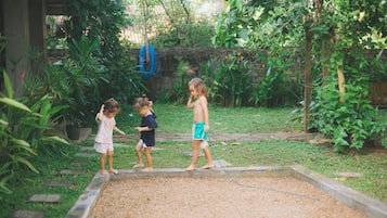A garden with a wooden play area and a blue hose.