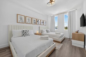 A hotel room with two beds, a flat-screen TV, and artwork on the wall. - GoUppers® Doppio | 5BR Townhome + Private Pool (Kissimmee)