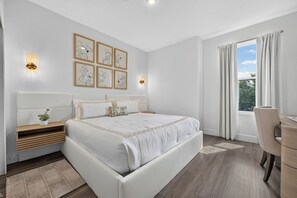 Ein modernes Schlafzimmer mit einem großen Bett, Nachttischen, einem Schreibtisch und einem Fenster mit Vorhängen.