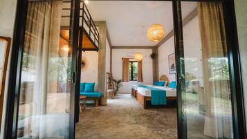 A spacious room with a large sliding glass door leading to an outdoor area, a bed with a blue bedspread, and a staircase.