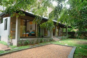Uma casa moderna com varanda coberta, caminho de pedra e área de jardim.