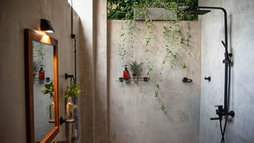 A modern bathroom with a large mirror, a shower, and shelves with toiletries.