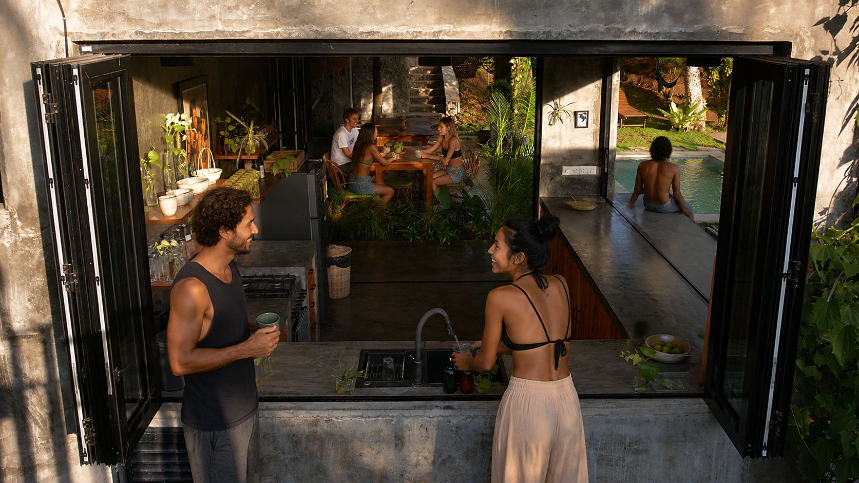 Une cuisine ouverte donnant sur une piscine et comprenant un coin repas.