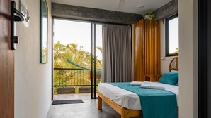 Ein Schlafzimmer mit Bett, Blick ins Freie und einem Balkon.