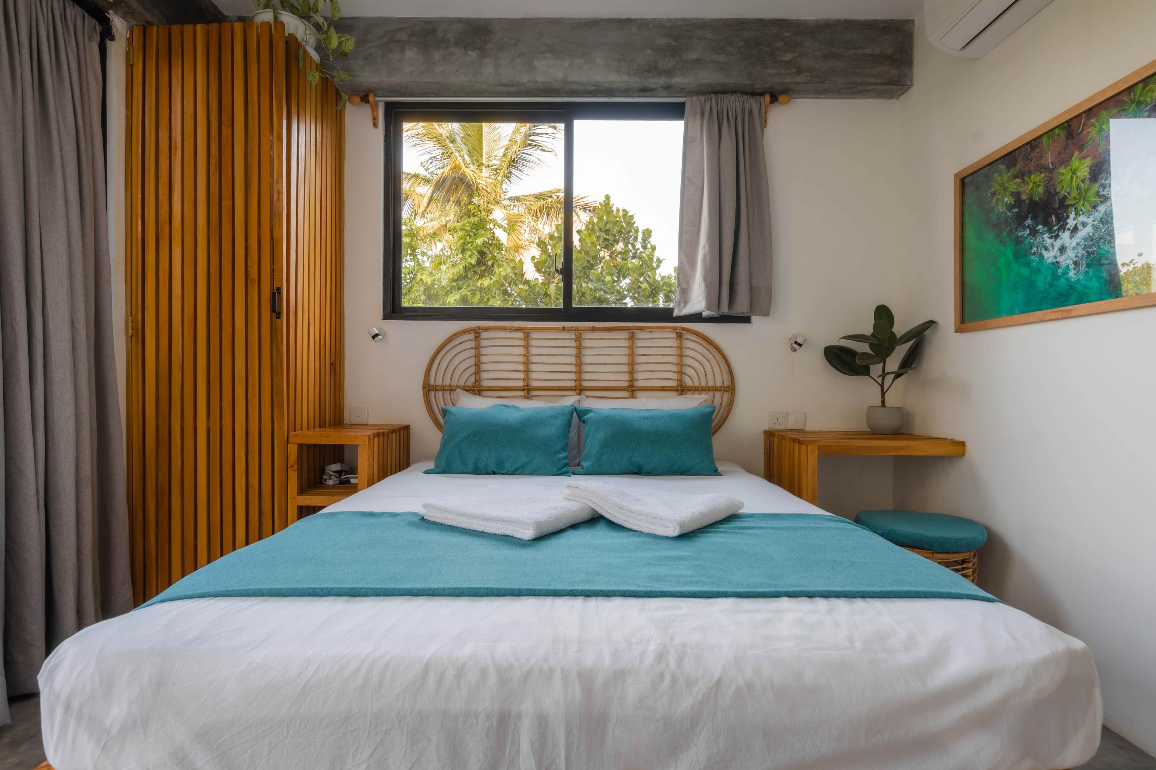Ein Schlafzimmer mit einem Bett, einem Fenster, einem Nachttisch und einer wandmontierten Pflanze.