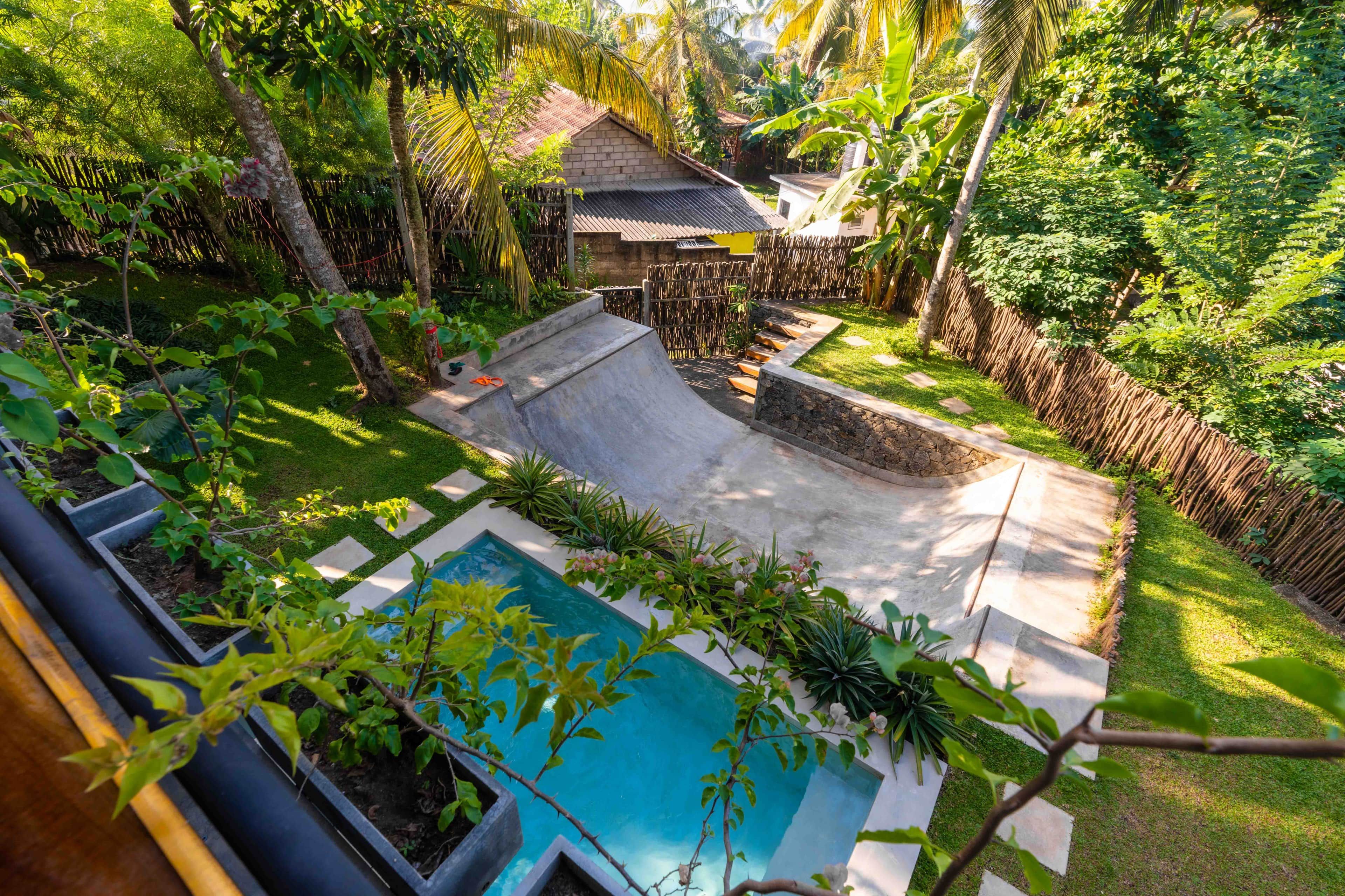 Ein Garten mit Swimmingpool, einer Holzterrasse und einem von Hecken umgebenen Bereich mit üppiger Bepflanzung.