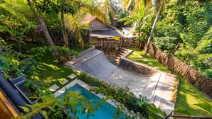 Quintal com piscina, deck de madeira e área cercada com vegetação exuberante.